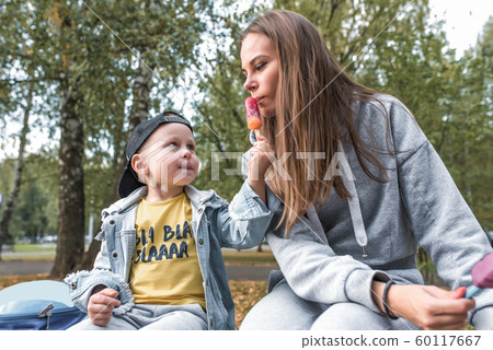 Family mother woman little boy son 4-5 years old, summer city autumn, eat vanilla ice cream, play fun, emotions relaxation weekend. Casual clothes, parenting support care love child. 60117667