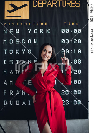 Happy woman in red dress and flight timetable. 60119630