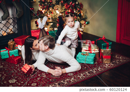 Family in presents next to Christmas tree. Family in presents next to Christmas tree. 60120124