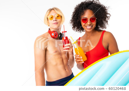 Pretty african female and caucasian blonde man stands in swimsuit with rubber beach mattresses Pretty african female and caucasian blonde man stands in swimsuit with rubber beach mattresses 60120468