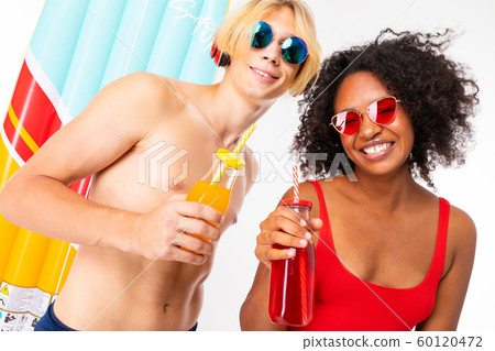 Pretty african female and caucasian blonde man stands in swimsuit with rubber beach mattresses Pretty african female and caucasian blonde man stands in swimsuit with rubber beach mattresses 60120472