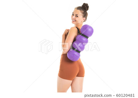 European brunette girl dressed in a brown sports top and shorts holds a massager behind her back on European brunette girl dressed in a brown sports top and shorts holds a massager behind her back on 60120481