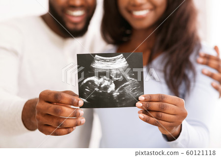 Smiling black couple holding ultrasound image, expecting baby 60121118