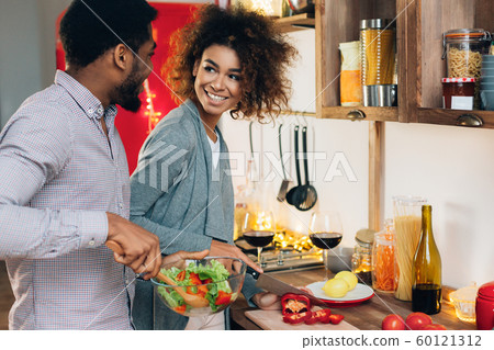 Vegetarian african-american couple cooking salad in kitchen