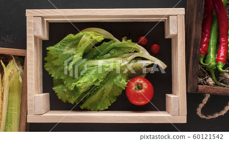 Fresh vegetables inside wooden box without bottom on black floor Fresh vegetables inside wooden box without bottom on black floor 60121542