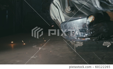 Forge workshop. Smithy. Worker in a welding hood helmet welds a part by electric welding. Sparks are reflected in the protective screen. Forge workshop. Smithy. Worker in a welding hood helmet welds a part by electric welding. Sparks are reflected in the protective screen. 60122265