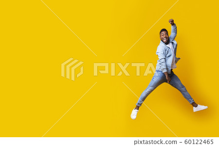 Portrait of jumping black guy on yellow studio background 60122465