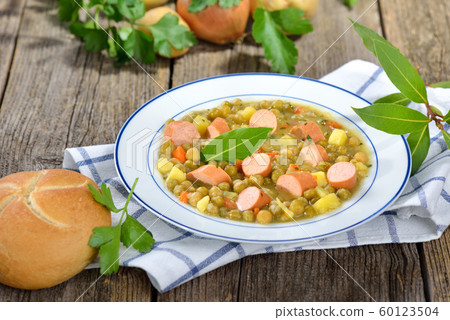 Hearty pea stew with potatoes, bacon and Viennese sausages served in a white plate Hearty pea stew with potatoes, bacon and Viennese sausages served in a white plate 60123504