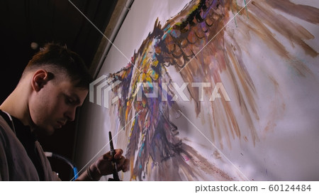 Artist designer draws an eagle on the wall. Craftsman decorator paints picture with acrylic oil color. Painter painter dressed in paint coat. Indoor. 60124484