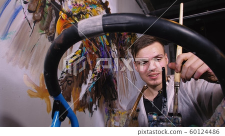 Artist designer draws an eagle on the wall. Craftsman decorator paints picture with acrylic oil color. Painter painter dressed in paint coat. Indoor. Artist designer draws an eagle on the wall. Craftsman decorator paints picture with acrylic oil color. Painter painter dressed in paint coat. Indoor. 60124486