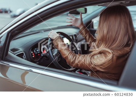 woman driving car jacket, shouting swearing negative accident stress on road, parking shopping center, fall city. Concept stress negative bad mood, emotions surprise, accident, conflict driving. 60124830