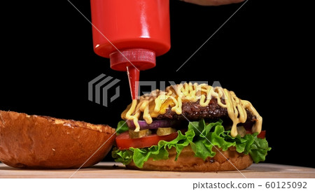 Craft burger is cooking on black background. Consist: sauce, lettuce, tomato, red onion, pickle, cheese, bacon, air bun and marbled meat beef. 60125092