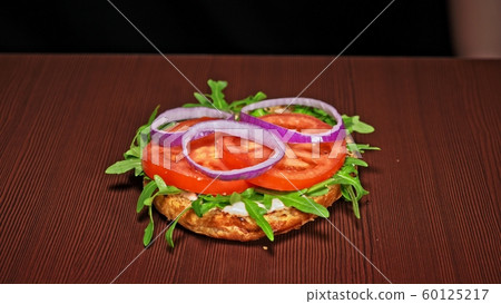 Craft burger is cooking on black background. Consist: sauce, arugula, tomato, onion, bacon, currant sauce, ricotta cheese, air bun and marble meat. 60125217