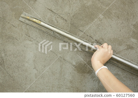 builder using trowel smoothing plaster on construction wall 60127560