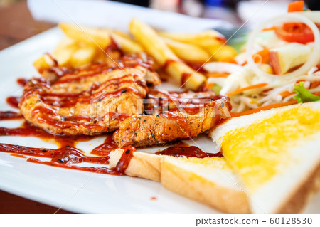 Grilled pork steak with salad on a plate Grilled pork steak with salad on a plate 60128530