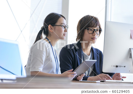 Young man and woman looking at computer monitor Young man and woman looking at computer monitor 60129405
