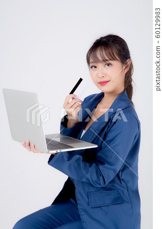 Beautiful young asian business woman happy holding credit card and laptop computer Beautiful young asian business woman happy holding credit card and laptop computer 60129983