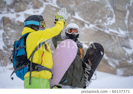 Image of two young athletes in helmet and mask doing handshake on background of mountain Image of two young athletes in helmet and mask doing handshake on background of mountain 60137371