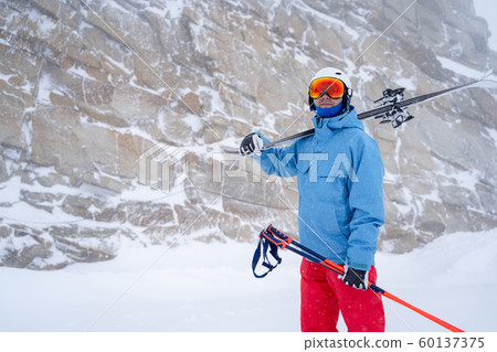 Image of sports man in helmet with skis in hand on background of mountain Image of sports man in helmet with skis in hand on background of mountain 60137375