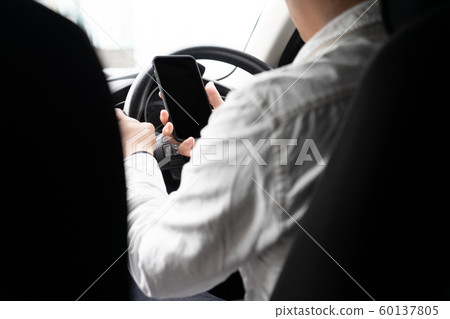 Man driving while operating smartphone Man driving while operating smartphone 60137805