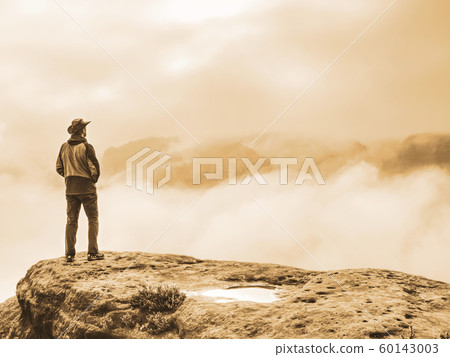 Hiker watching over misty valley to blurred Hiker watching over misty valley to blurred 60143003