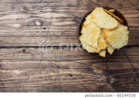 Potato fluted chips with spices in a wooden bowl on a wooden table. copy space. Potato fluted chips with spices in a wooden bowl on a wooden table. copy space. 60144530