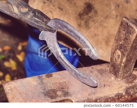 Blacksmith working on the anvil, making a Blacksmith working on the anvil, making a 60144575
