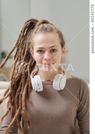 Pretty smiling girl in pullover with headphones around her neck Pretty smiling girl in pullover with headphones around her neck 60145779