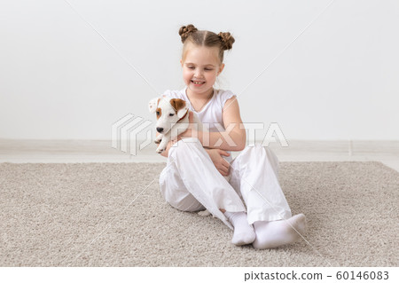 Pet, childhood and animal concept - Portrait of little child girl sitting on the floor with puppy Jack Russell Terrier Pet, childhood and animal concept - Portrait of little child girl sitting on the floor with puppy Jack Russell Terrier 60146083