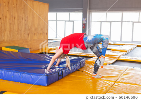 Young woman sportsman on a trampoline in fitness park and doing exercise indoors Young woman sportsman on a trampoline in fitness park and doing exercise indoors 60146690