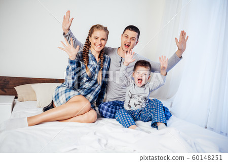 mom dad and son in the morning lying on the bed at home mom dad and son in the morning lying on the bed at home 60148251