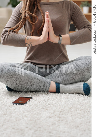 Active female sitting on the floor with crossed legs during yoga exercise 60148436