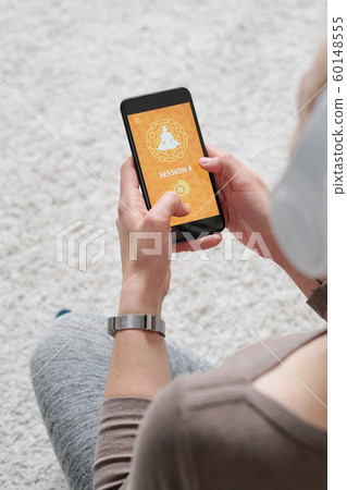 Hands of young active female holding smartphone while listening to audio Hands of young active female holding smartphone while listening to audio 60148555