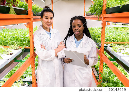 One of two young female agronomists making notes while studying new plants 60148639