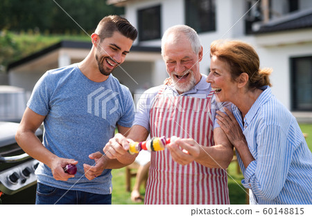Portrait of multigeneration family outdoors on garden barbecue, grilling. 60148815