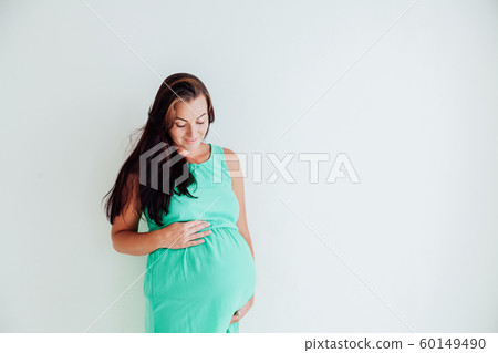 a pregnant woman is standing at the wall next to the window a pregnant woman is standing at the wall next to the window 60149490
