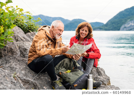 A senior pensioner couple hiking by lake in nature, using map. A senior pensioner couple hiking by lake in nature, using map. 60149968