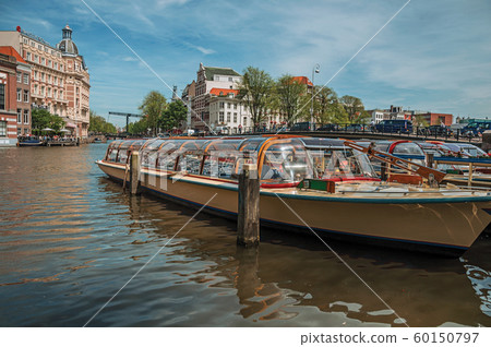 Boats moored at canal side and brick buildings in Amsterdam 60150797
