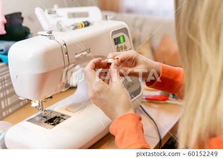 seamstress winding thread from spool to bobbin, seamstress winding thread from spool to bobbin, 60152249
