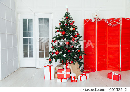 Christmas tree with red gifts December decor in the interior of the white room as a background 60152342