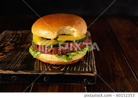 Bitten vegetarian burger on wooden board on dark background 60152353