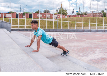 Male athlete doing push-ups and training abdominal muscles plank workout, summer in city. Fitness motivation youth lifestyle. Free space for copy text. 60154604