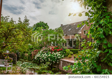 Canal next to rustic house and lush flowery garden Canal next to rustic house and lush flowery garden 60154915