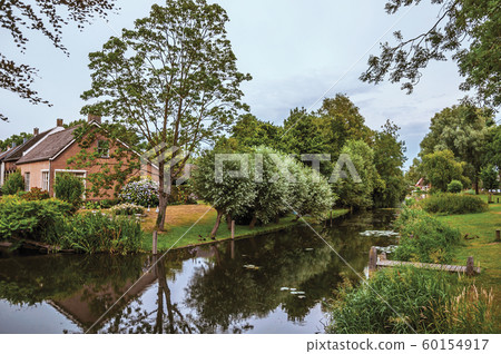 Canal next to rustic house with garden and trees Canal next to rustic house with garden and trees 60154917