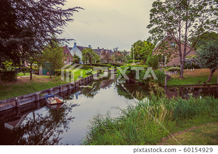Canal next to rustic houses with gardens and trees Canal next to rustic houses with gardens and trees 60154929