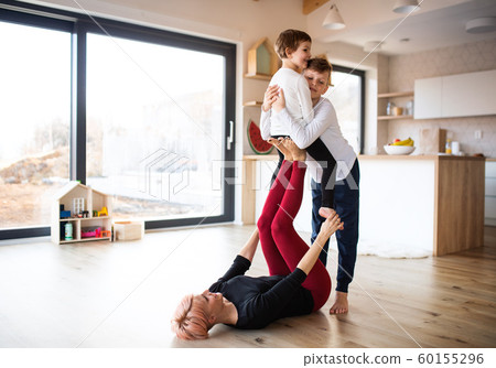 A young woman with two children playing on the floor, having fun. A young woman with two children playing on the floor, having fun. 60155296