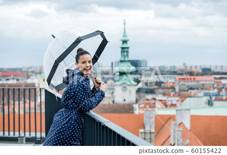 A young woman with umbrella standing on a terrace, resting. A young woman with umbrella standing on a terrace, resting. 60155422