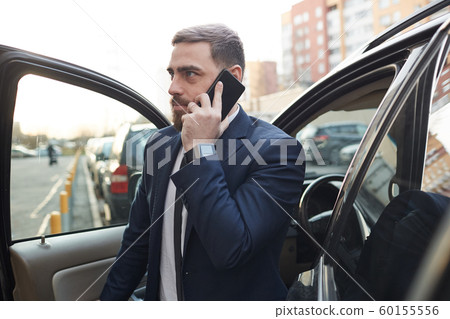 Businessman coming out the car in the city 60155556