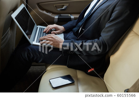 Businessman working on laptop in the car Businessman working on laptop in the car 60155566