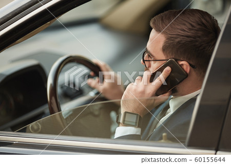 Busy businessman driving his car Busy businessman driving his car 60155644